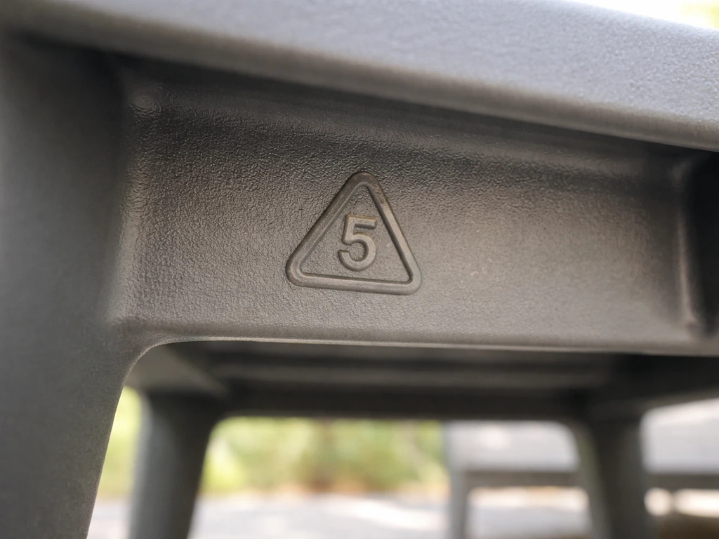 Close-up of the underside of patio furniture showing a molded resin identification code triangle with a number