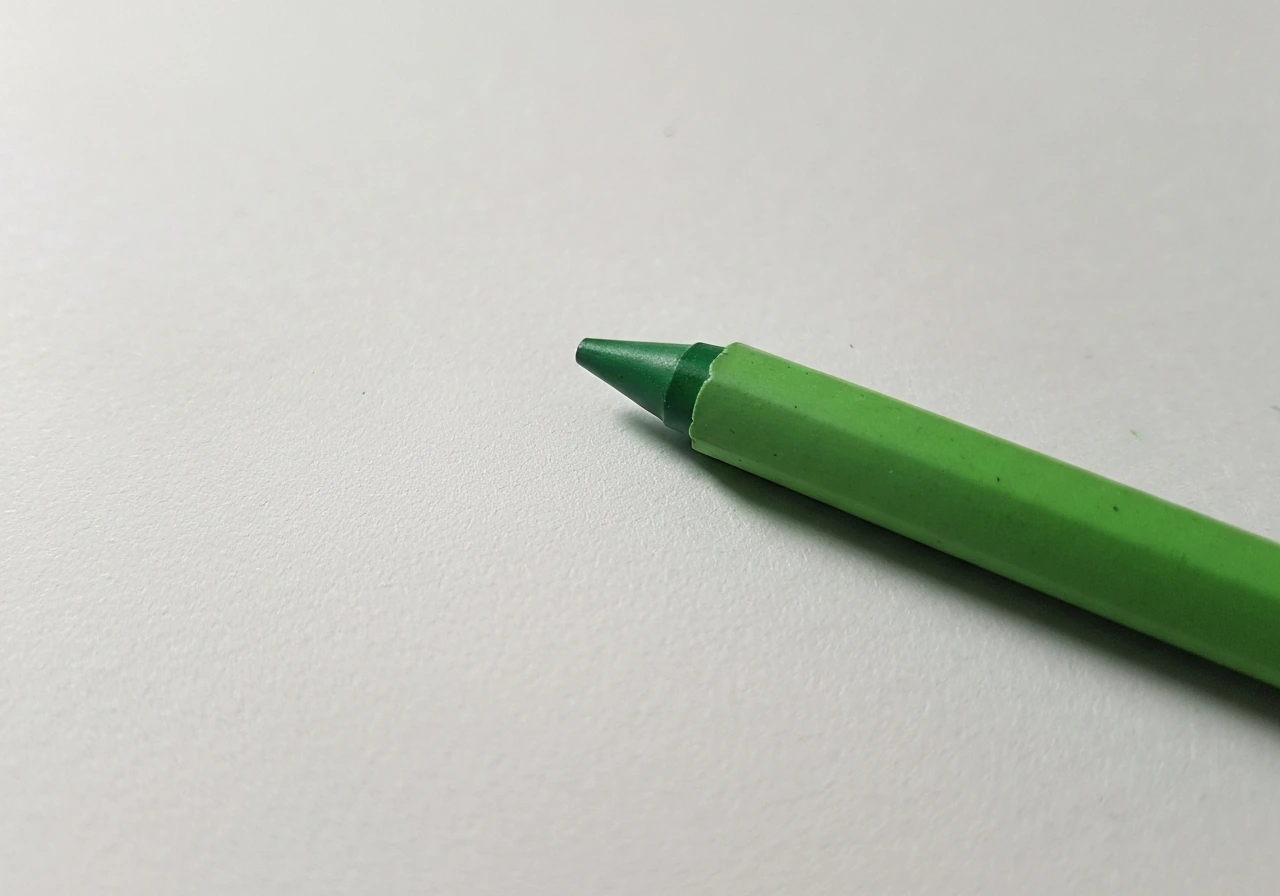 Crayon vert posé sur une feuille texturée, avec un fondu doux de couleur sans aplats