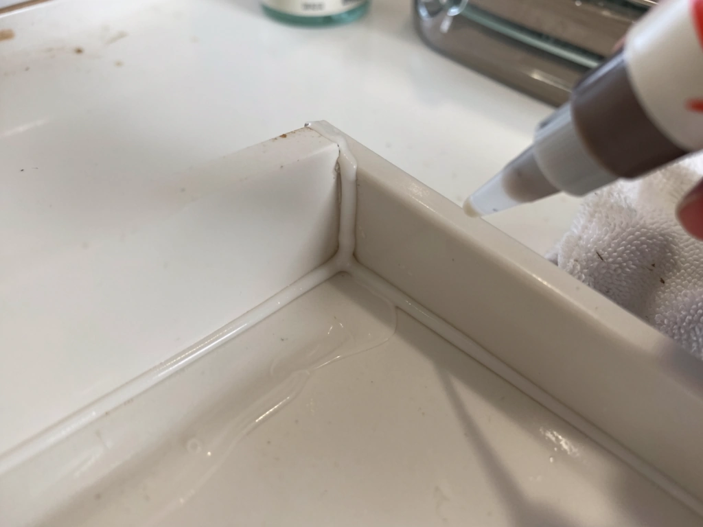 Applying 100% silicone bead inside tray corners to seal gaps
