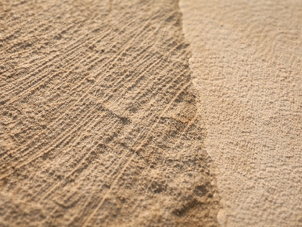 Aggressive wire-brushed scratches on soft sandstone/limestone texture with nearby cleaner stone area