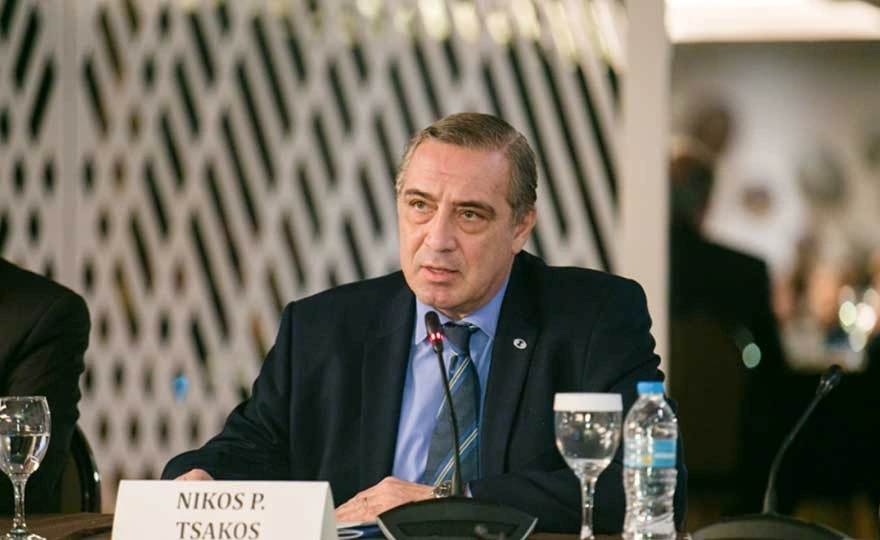 Nikolas P. Tsakos speaking at a conference table in a formal setting