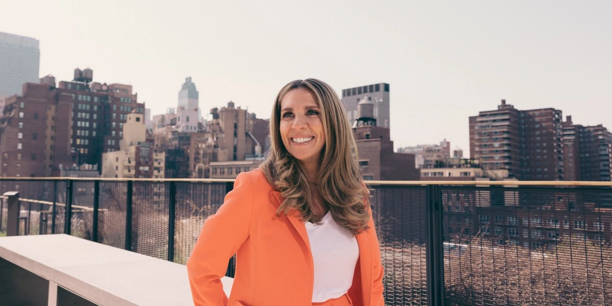 Nicola Mendelsohn smiling outdoors on a rooftop with a city skyline in the background