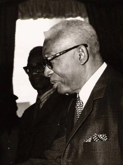 François Duvalier in profile, wearing glasses and a suit
