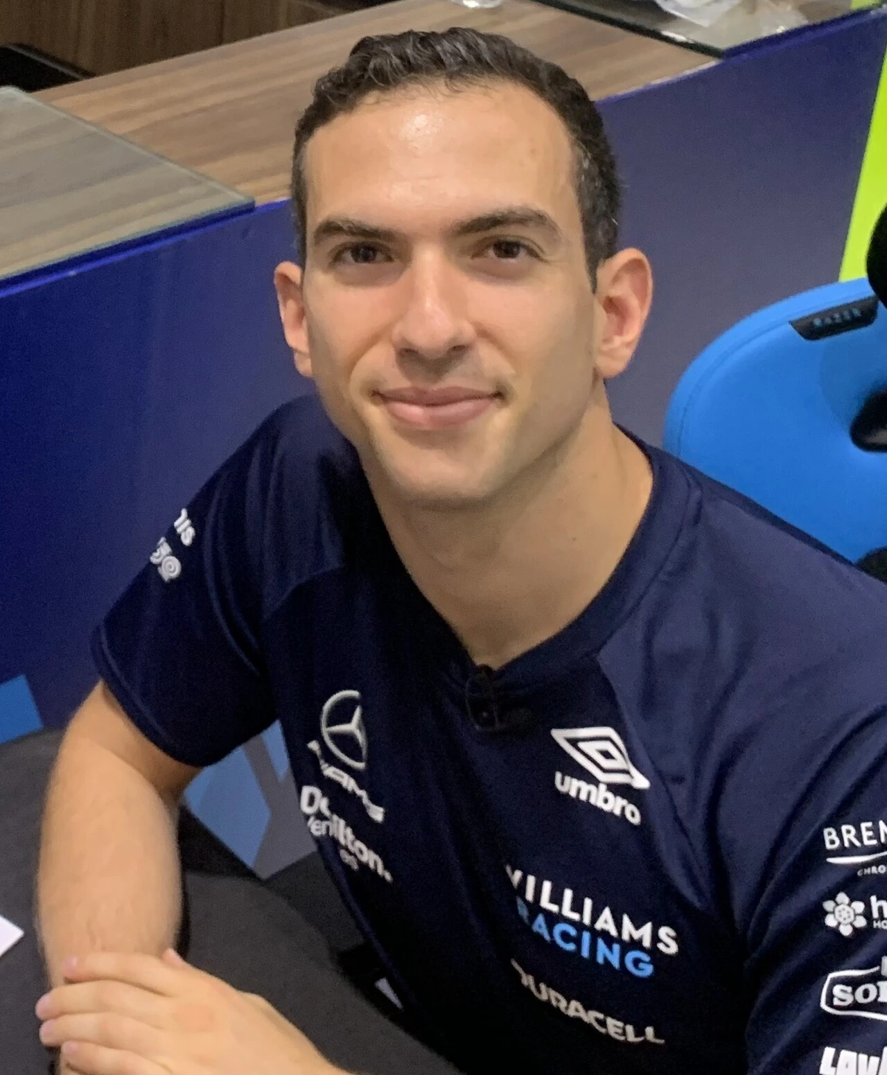 Nicholas Latifi smiling in a Williams Racing shirt indoors
