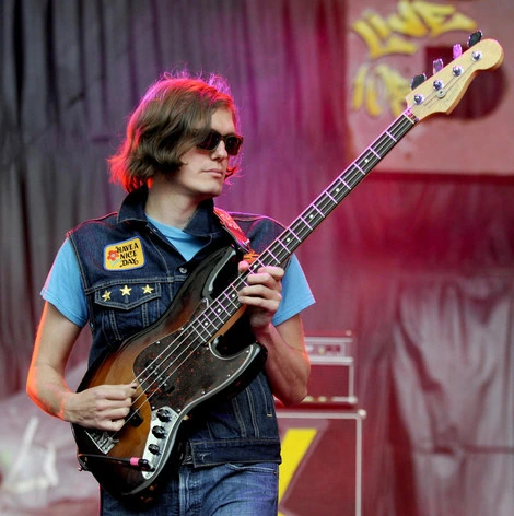 Nikolai Fraiture performing on bass guitar at a live concert.