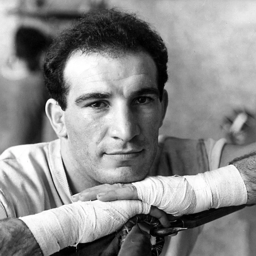 Black-and-white portrait of Argentine boxer Nicolino Locche resting his wrapped hands and looking at the camera