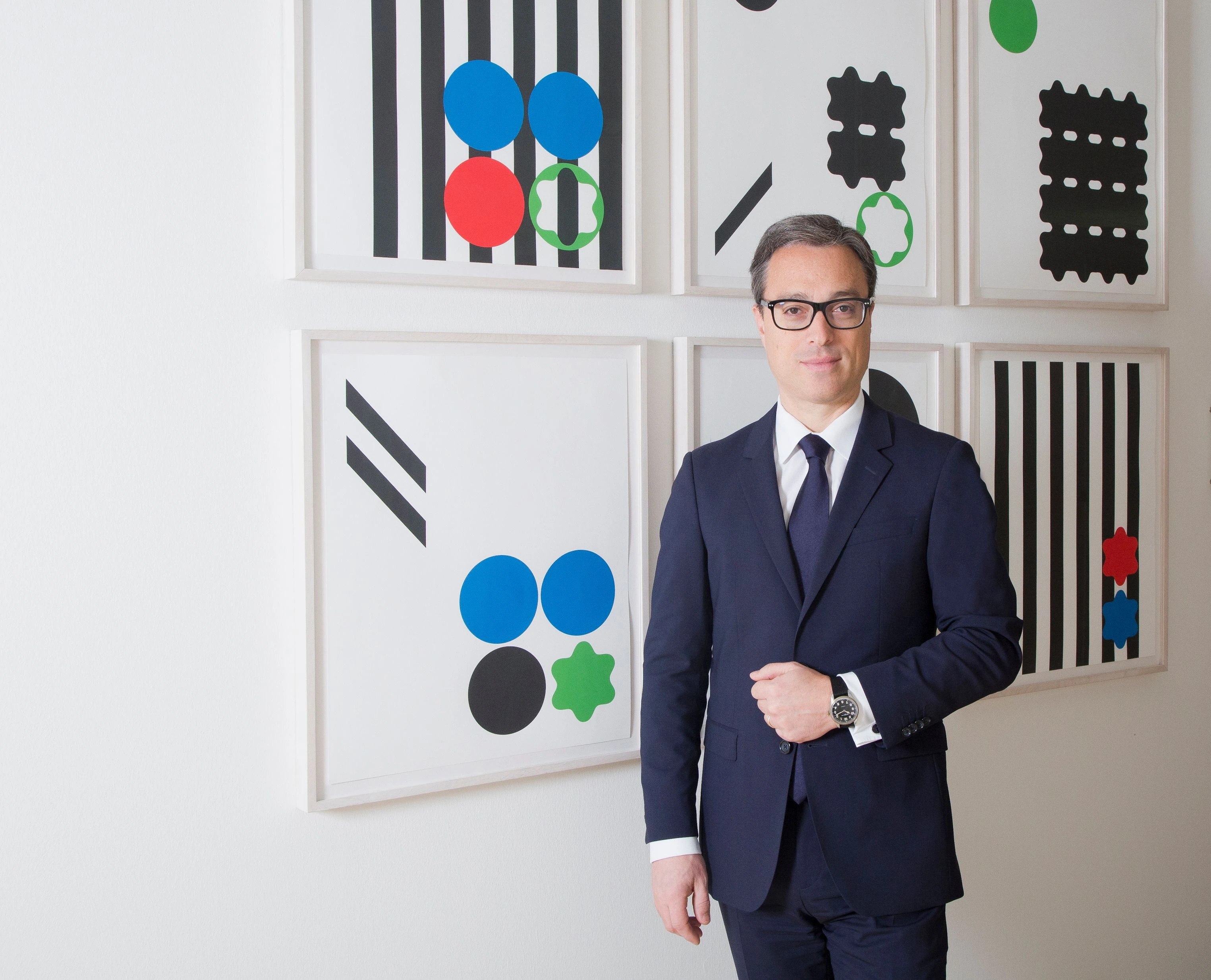 Portrait of Nicolas Baretzki, Montblanc CEO, standing in a suit in front of framed artwork