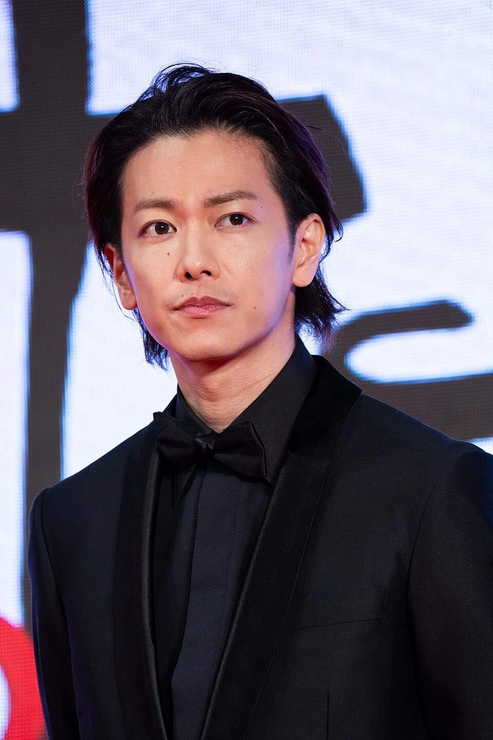 Japanese actor Takeru Satoh at a Tokyo International Film Festival event, wearing a black tuxedo against a lit backdrop.