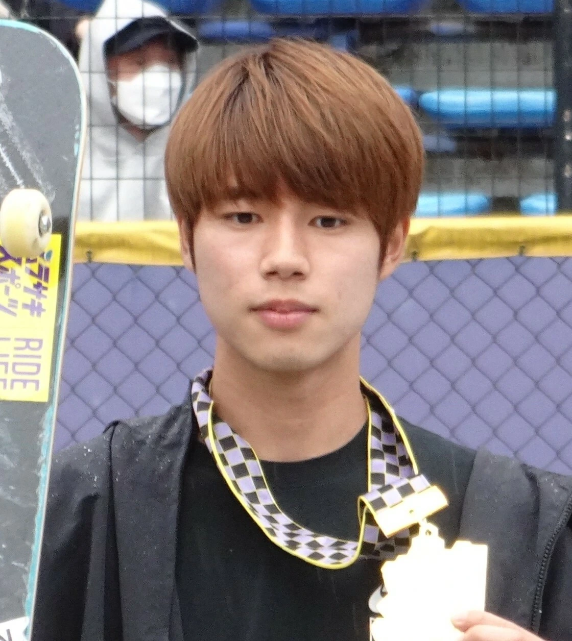 Yuto Horigome holding a skateboard and trophy at an event