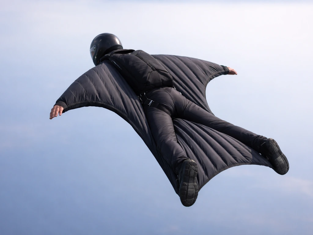 A wingsuit flyer in stable freefall over open sky, fabric wing surfaces inflated for controlled glide.