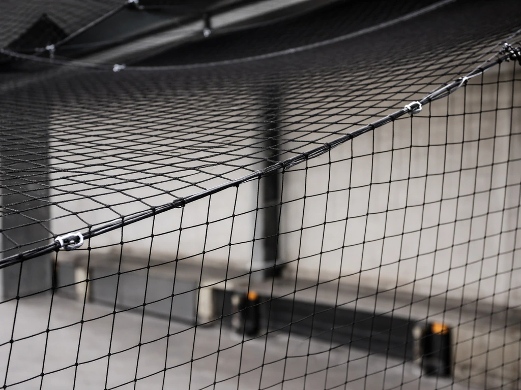 Taut black bird netting secured across a courtyard/loading dock to physically block birds from entering.