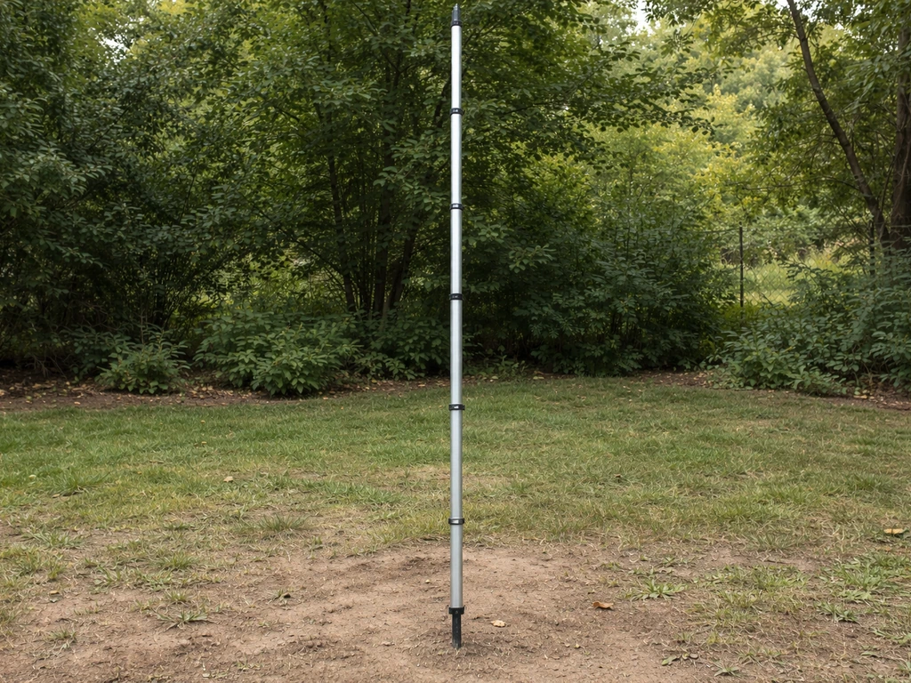 Modular pole segments assembled outdoors near a ground stake, showing the full height profile