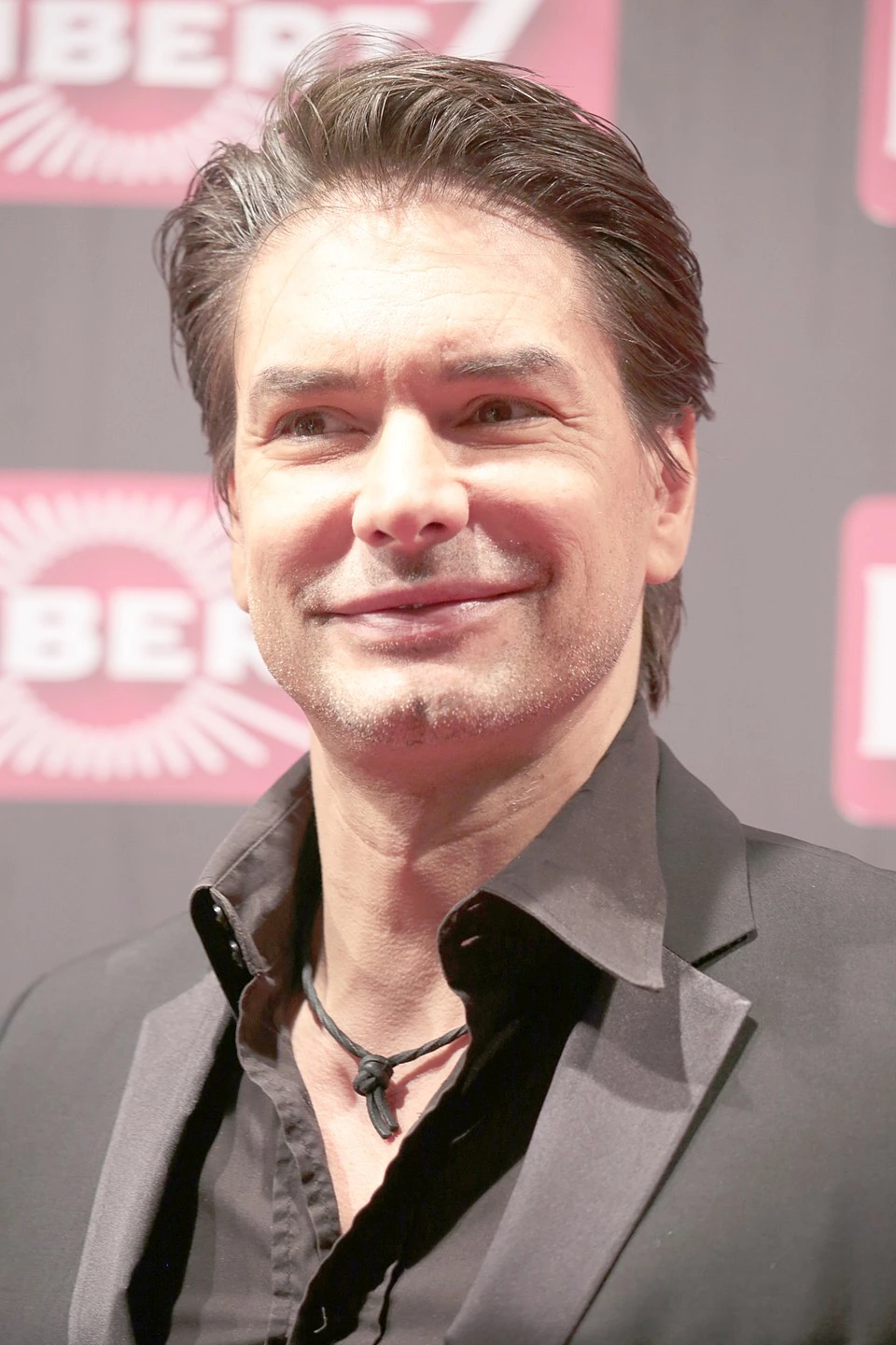 Marcus Schenkenberg smiling on the red carpet in a black suit