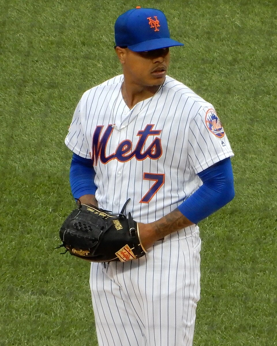 Marcus Stroman in a New York Mets uniform on the field during a game, holding a baseball glove.