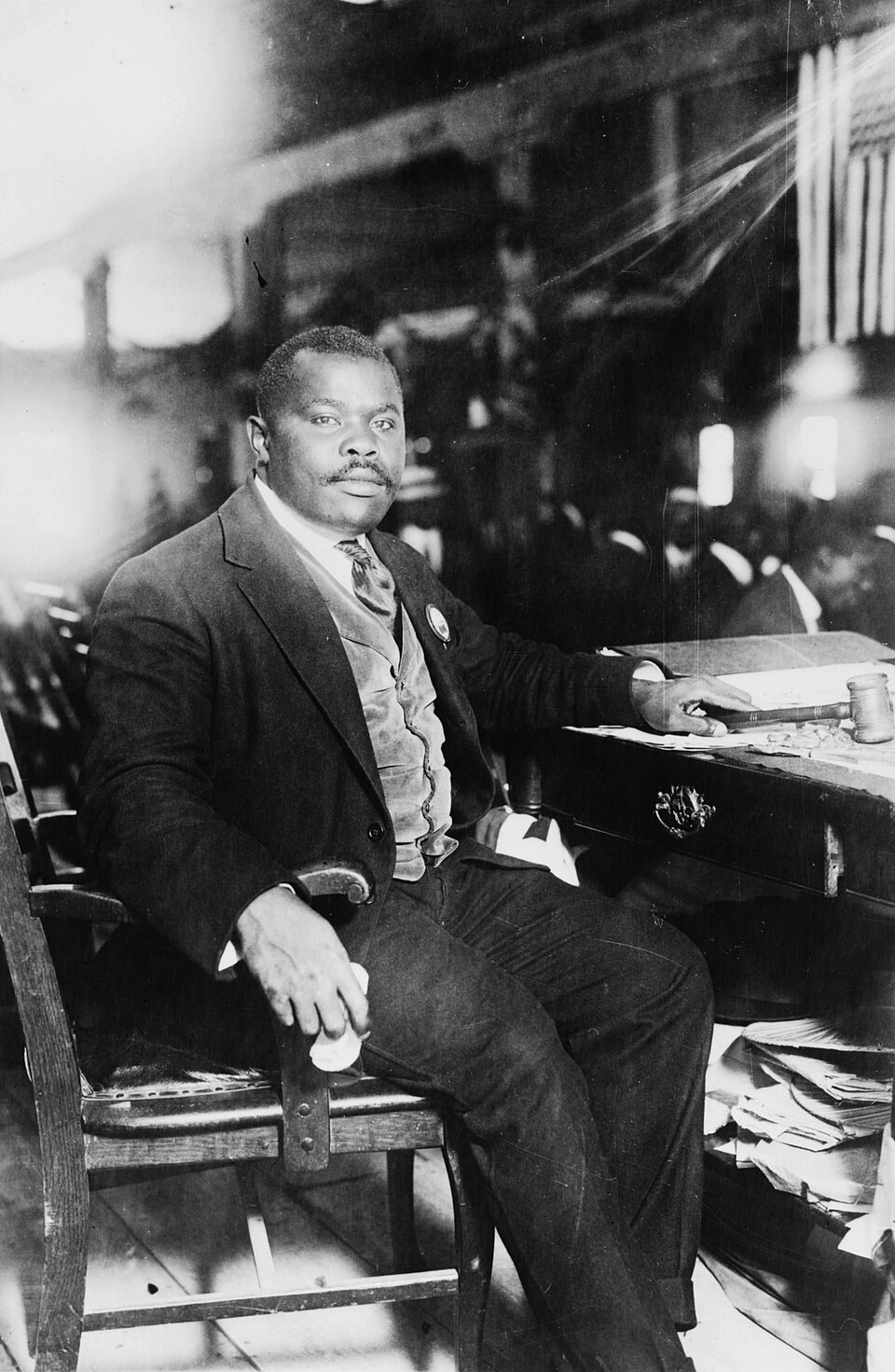 Marcus Garvey seated at a desk in a black-and-white historical photograph.