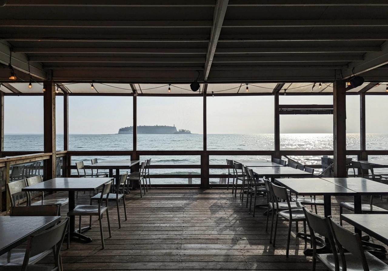 Wide view of a screened-in patio with waterfront seating and a clear view of Mackinac Island in the distance.