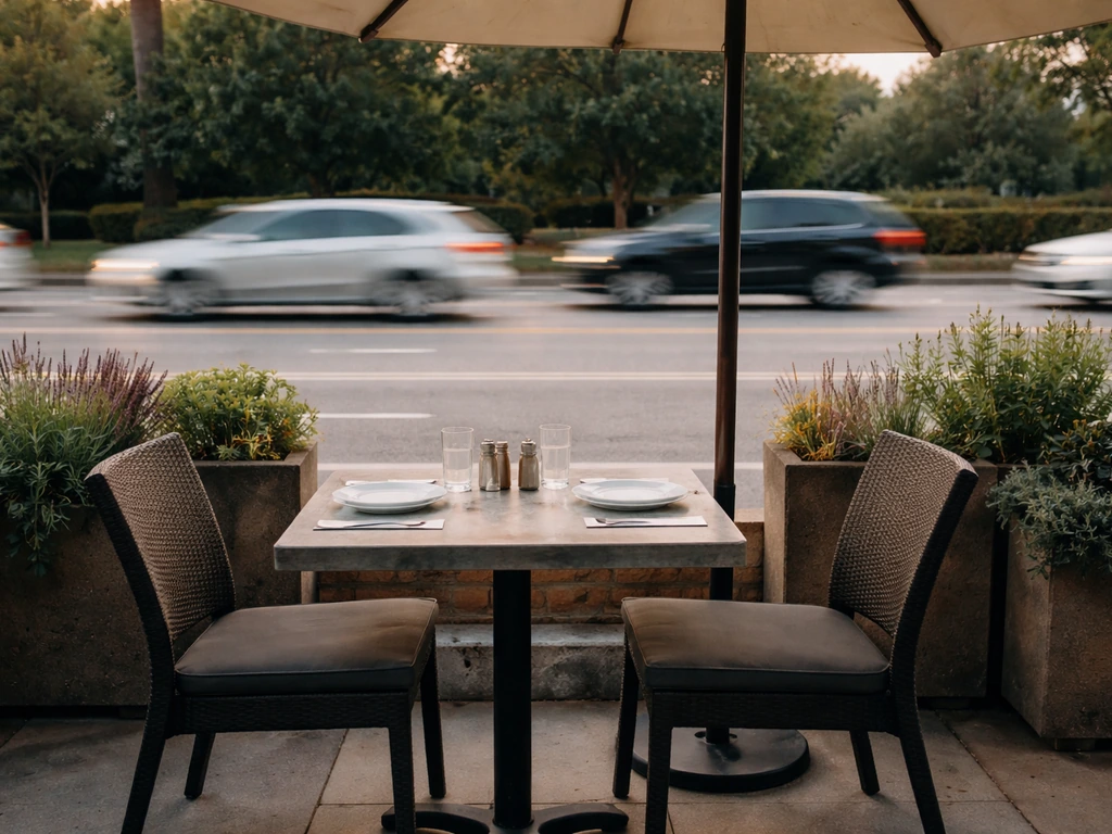 Quiet patio beside a busy road with cars passing and street noise ambience implied