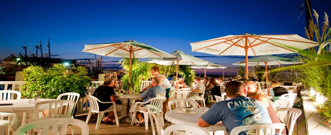 Outdoor patio dining area at The Shrimp Box and Outside the Box Patio Bar with tables, umbrellas, and waterfront evening