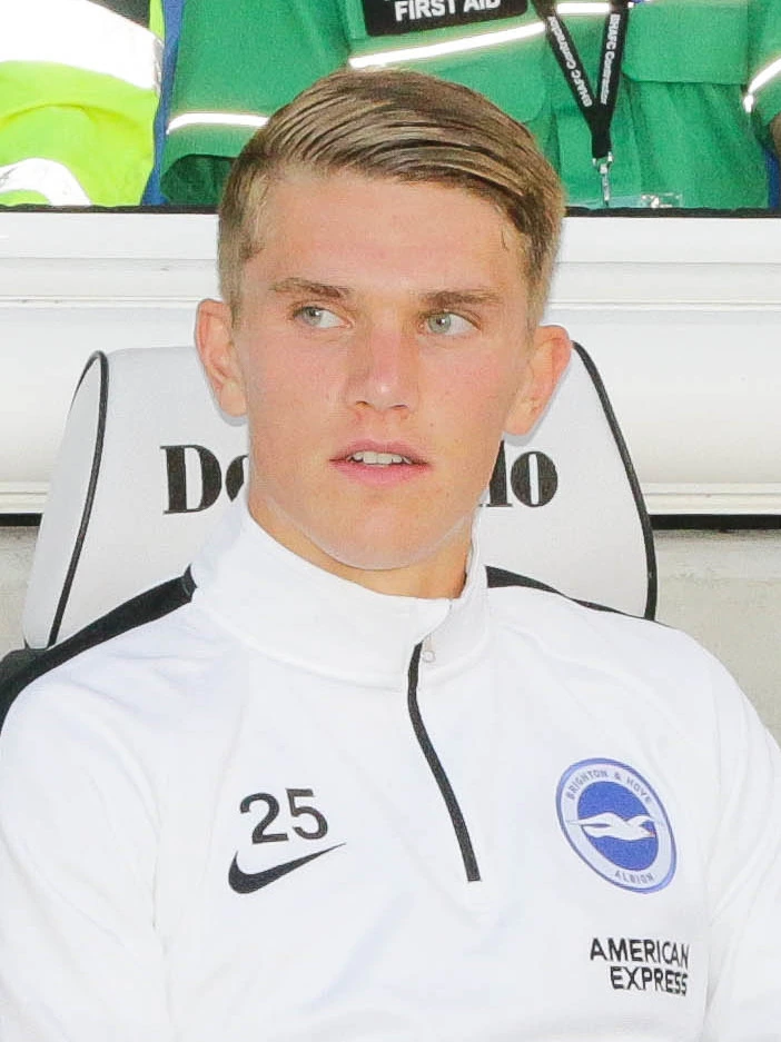 Viktor Gyökeres seated in a team bench wearing a white jacket