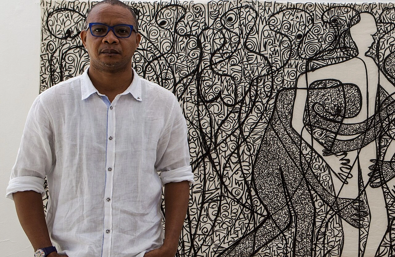 Victor Ehikhamenor standing in front of a large black-and-white artwork