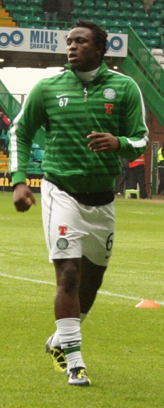 Victor Wanyama warming up on a football pitch in a green training jacket and white shorts