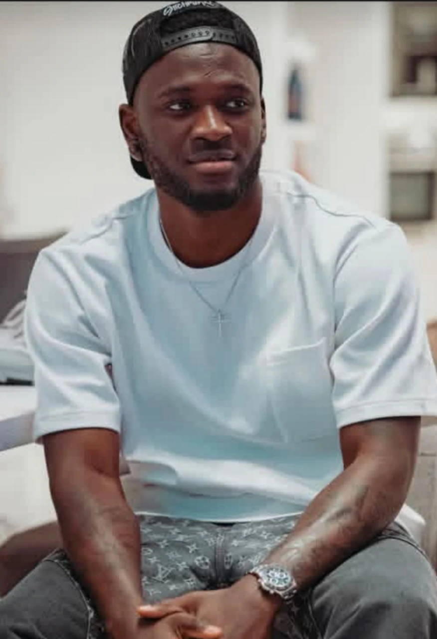 Victor Boniface seated indoors wearing a backwards black cap and a light blue shirt