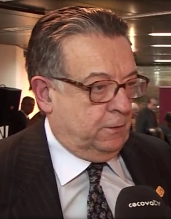Portrait photo of Victor Herrero Amigo at an event, wearing glasses and a suit while speaking into a microphone.