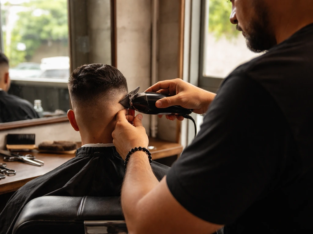 Barber trimming hair in a quiet Puerto Rico barbershop, hands and tools in focus, face not shown.