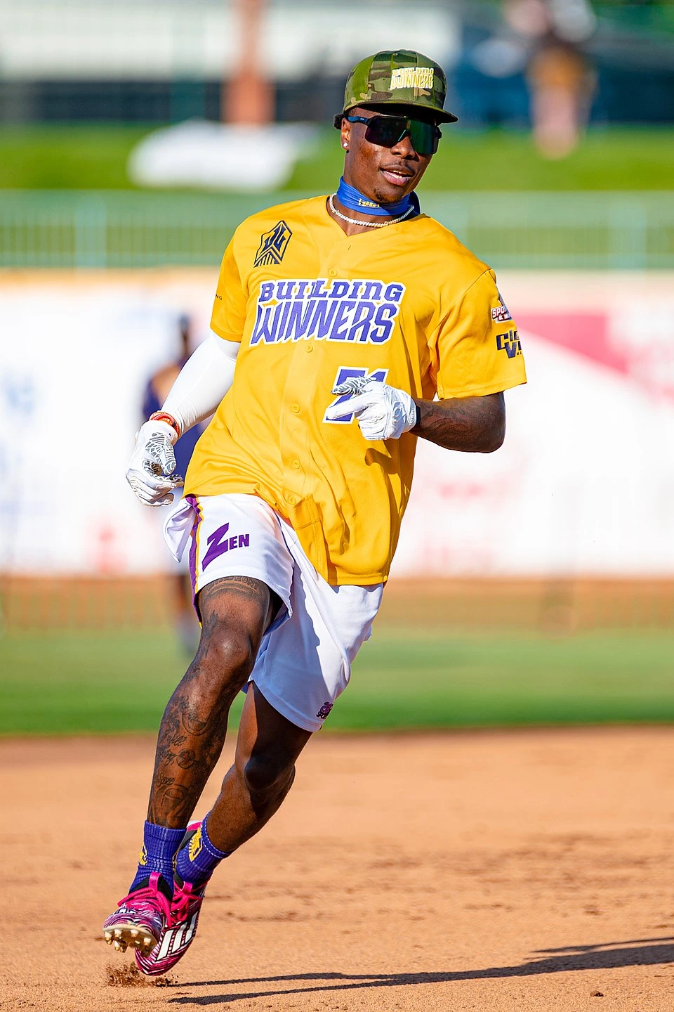 Henry Ruggs III in a yellow jersey and camo cap on a baseball field.