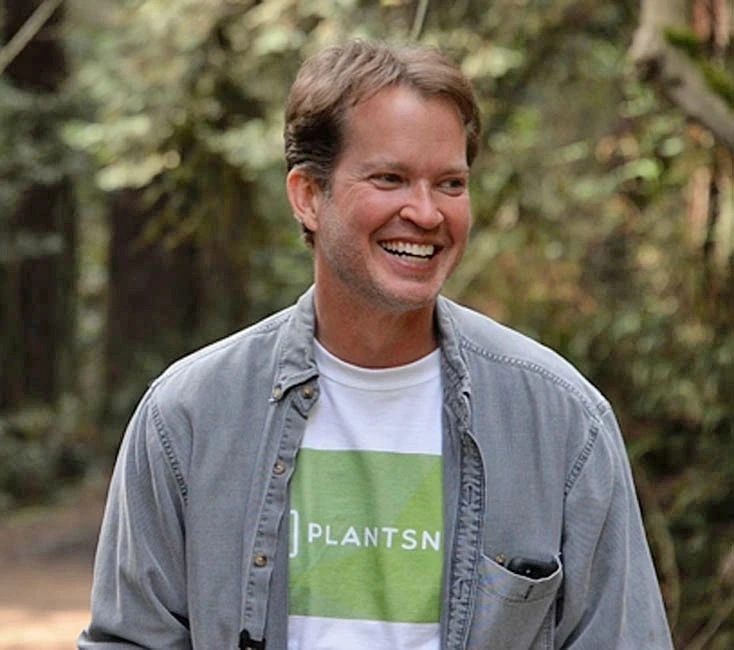 Eric Ralls smiling outdoors wearing a PlantSnap shirt