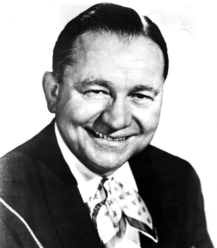 Black-and-white portrait of Tex Ritter smiling in a suit and tie