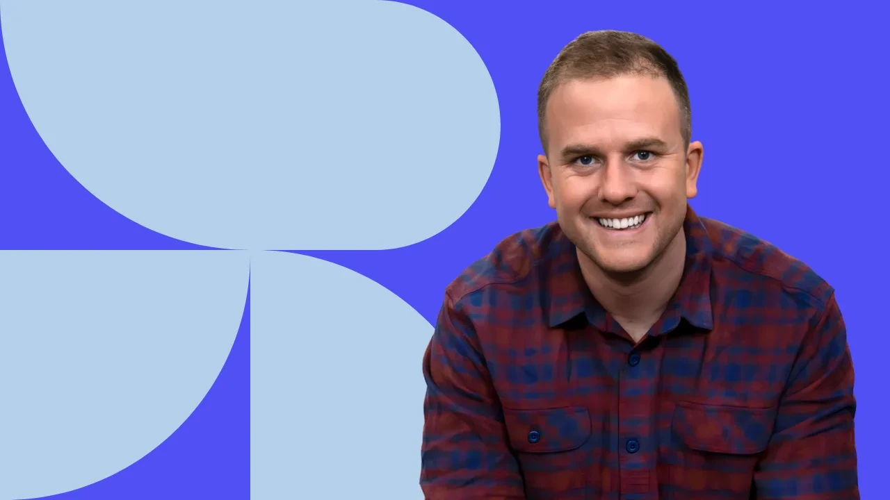 Portrait of Owen Raszkiewicz smiling against a graphic blue background