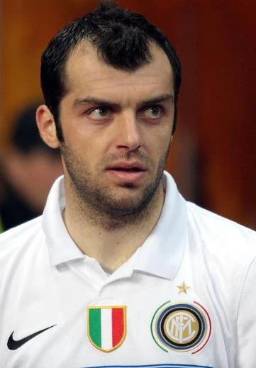 Goran Pandev in a white football shirt, looking off to the side during a match or event.