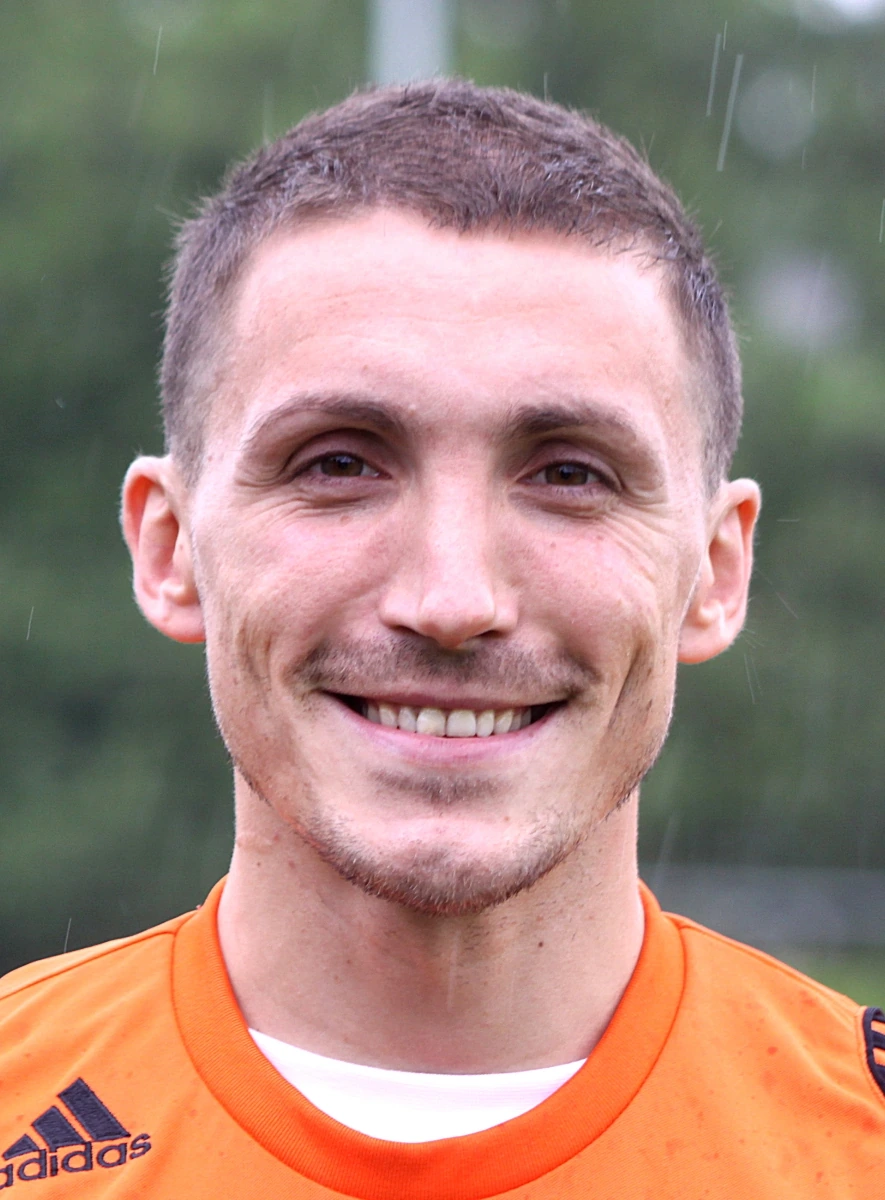 Portrait photo of Filip Đorđević in an orange football jersey outdoors.