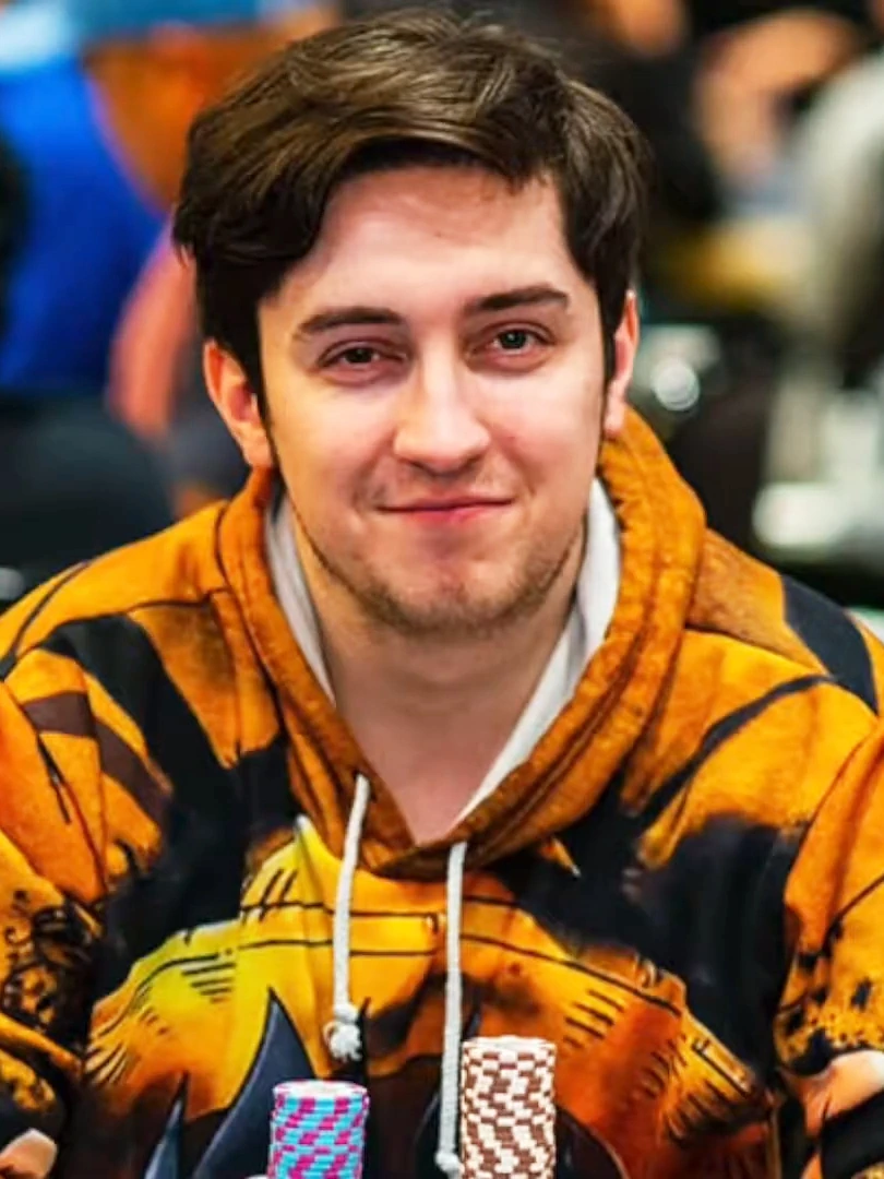 Portrait of Ali Imširović at a poker table wearing a patterned hoodie, with poker chips in the foreground.
