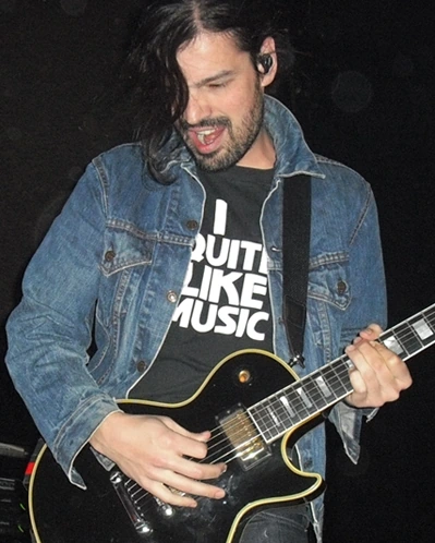 Tomo Miličević performing with a guitar onstage