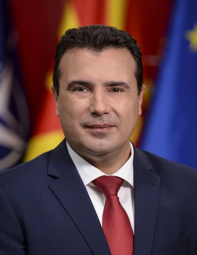 Official portrait of Zoran Zaev, former Prime Minister of North Macedonia, in a suit and tie against a flag background.