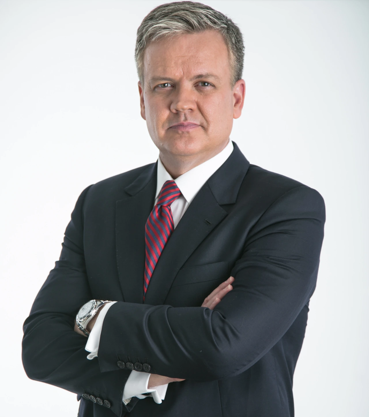 Portrait of Xavier Serbiá in a dark suit and striped tie against a light background