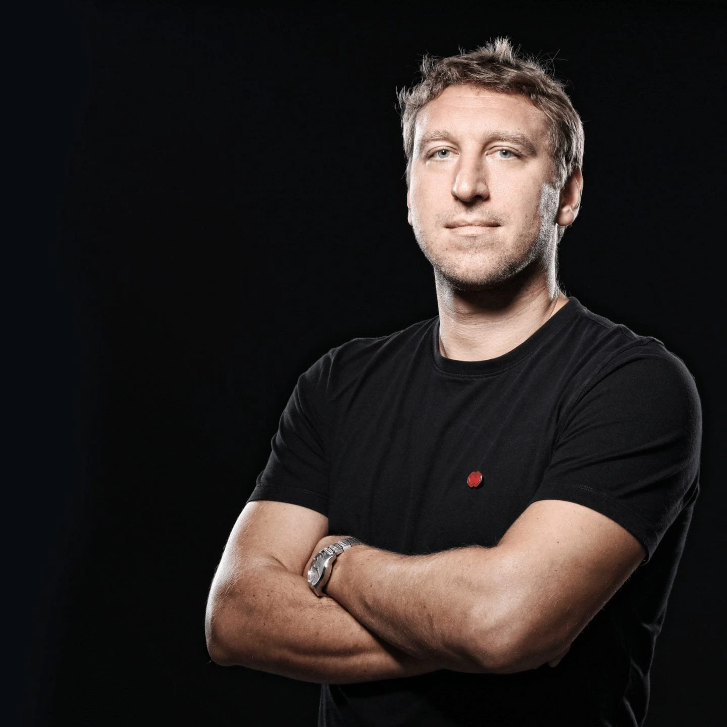 Portrait photo of Branko Milutinović standing with arms crossed against a dark background