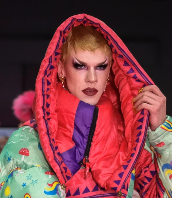 Utica Queen posing in a colorful runway look at DragCon 2023, a close-up editorial-style photo of the drag performer and