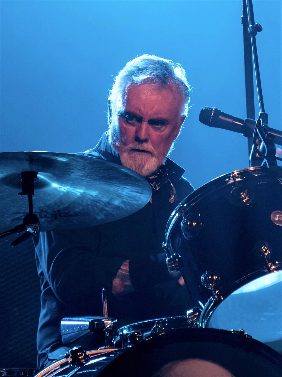 Roger Taylor playing drums on stage during a live performance