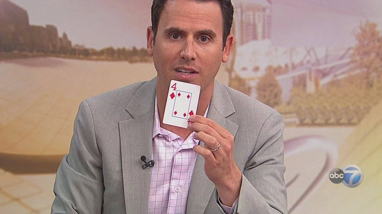Oz Pearlman holding up a playing card during an ABC7 interview segment.