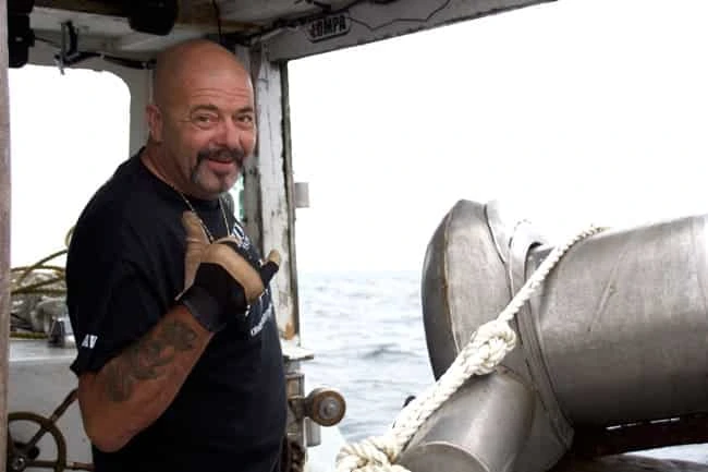 Dave Marciano standing aboard a fishing boat at sea, looking toward the camera