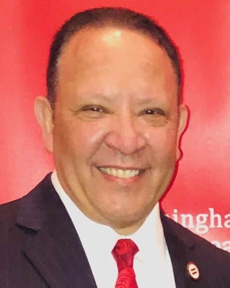 Marc Morial smiling in a red-background portrait