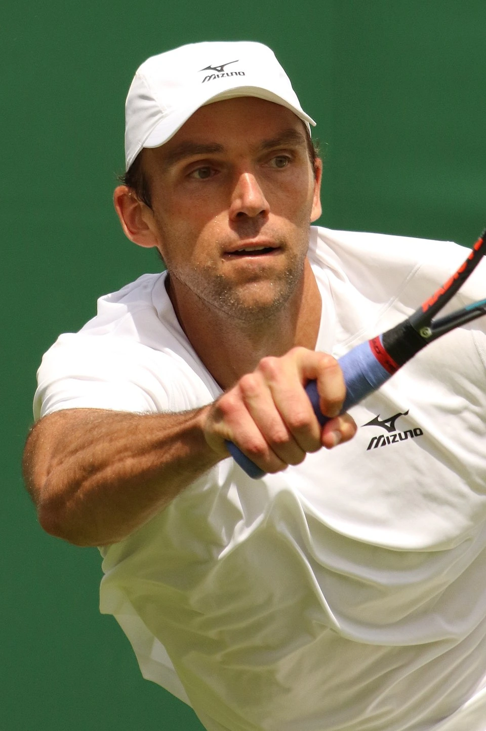Ivo Karlović playing tennis in a white cap and shirt