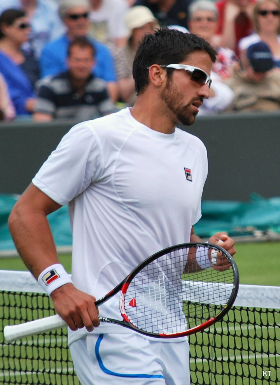 Janko Tipsarević on court holding a tennis racket, wearing a white shirt and sunglasses during a match