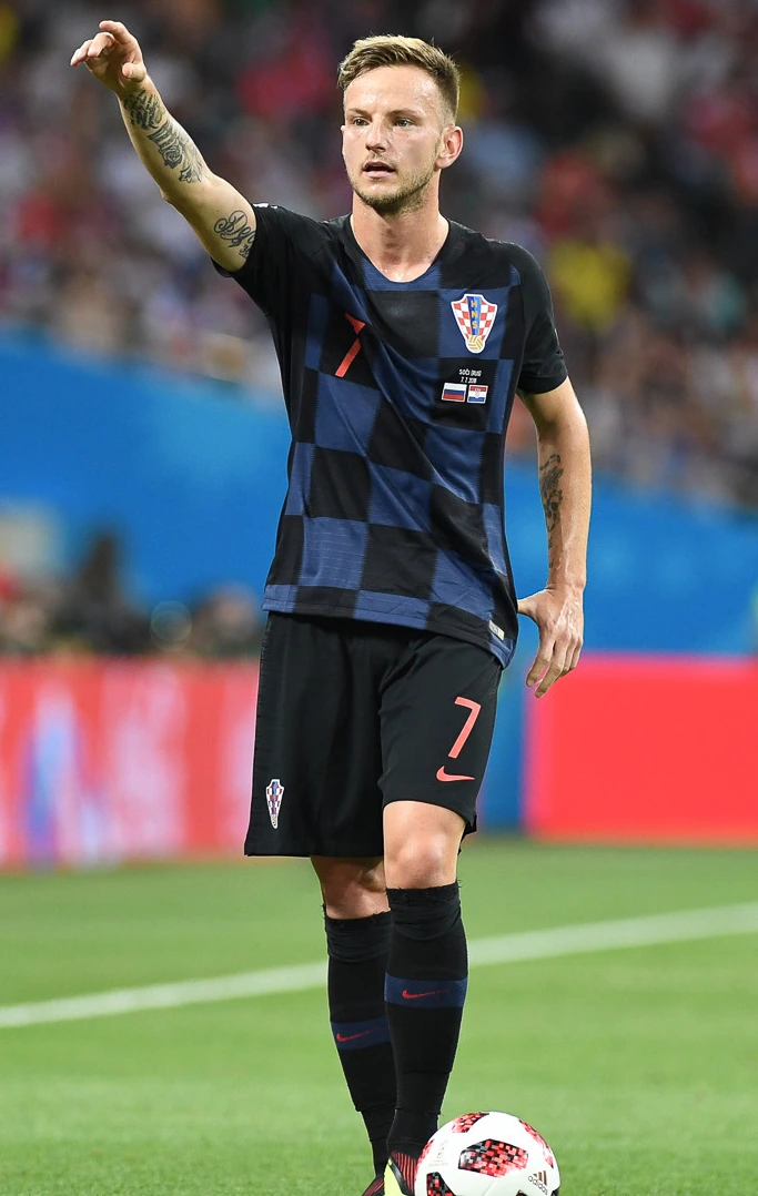 Ivan Rakitić in Croatia national team kit on the pitch during a football match, raising one arm with a stadium backgroun