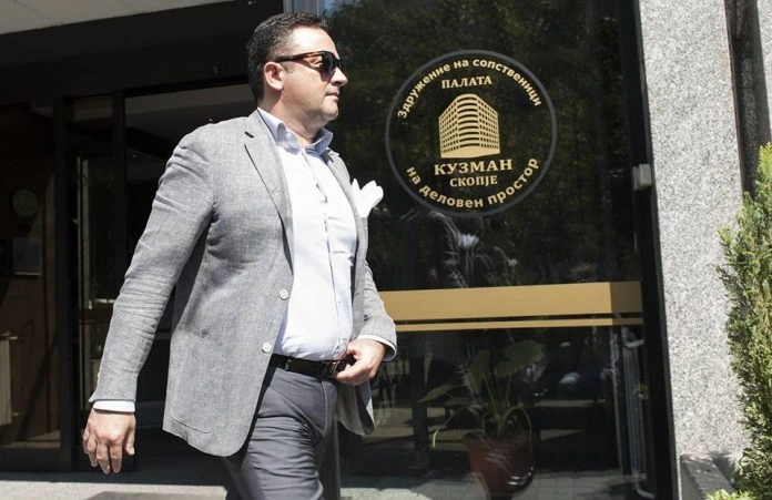 Orce Kamcev walking outside a building in a gray blazer and sunglasses