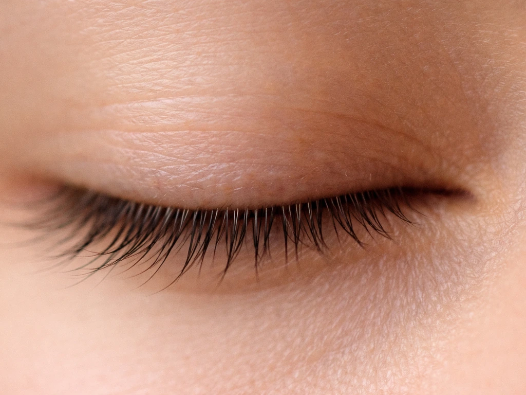 Extreme close-up of a lash line with mixed lash lengths and slight patchiness along an eyelid.