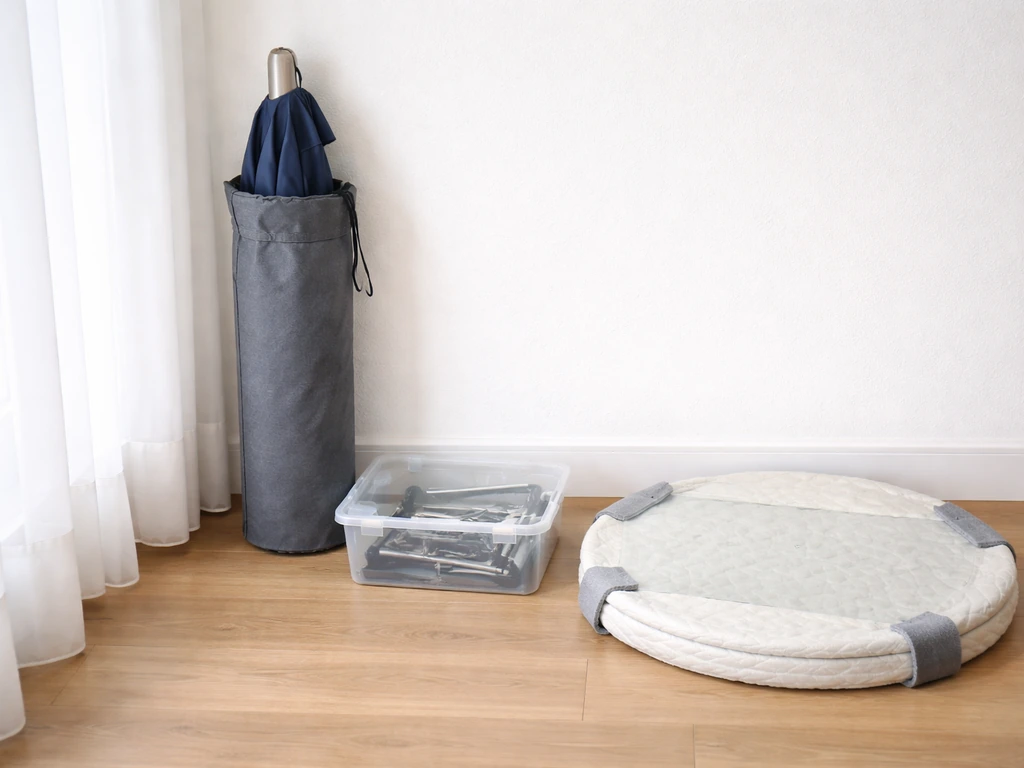 Umbrella stored separately with wrapped glass tabletop and small hardware pieces in a lidded bin.